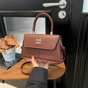 Dark brown leather handbag with a top handle and shoulder strap on a wooden surface