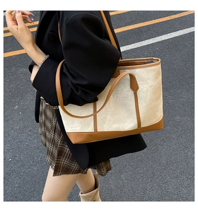 Detail of canvas and brown leather tote bag showing shoulder strap and handle texture