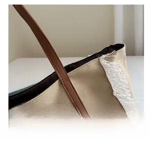Gros plan sur les coutures renforcées d'un sac cabas en toile avec sangle marron