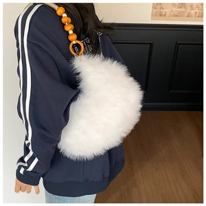 Detail of white faux fur shoulder bag with orange beaded handle on female model
