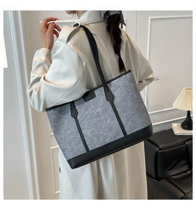 Detailed side view of large grey felt tote bag with black leather straps on model