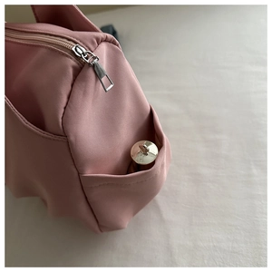 Detail of pink nylon shoulder bag with silver zipper and functional side pocket