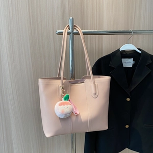 Fashionable peach-orange leather tote bag with a cute peach plush pendant and long straps