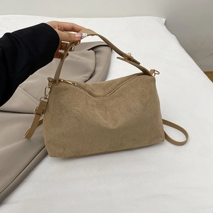 Braune Wildleder-Umhängetasche mit goldenen Details und passendem Blazer auf weißem Laken
