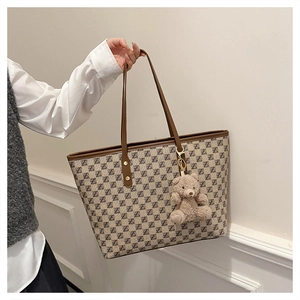 Detail of monogram tote bag with brown leather handles and cute teddy bear charm