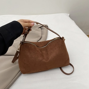 Braune Wildleder-Handtasche mit goldenen Beschlägen und Schultergurt in Lifestyle-Szene