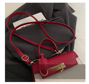Detail of red leather and plaid patchwork handbag with gold clasp on grey background