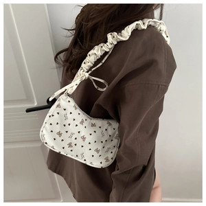 Detail of white corduroy shoulder bag with brown sweet prints and ruffled cloud strap
