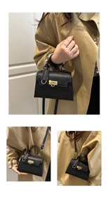 Nahaufnahme der schwarzen Handtasche aus Leder mit goldenem Drehverschluss und Schultergurt