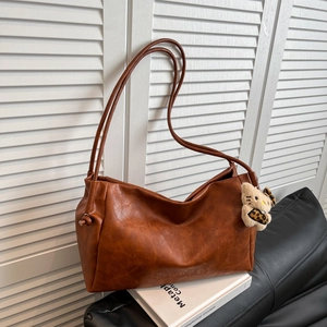 Brown vintage faux leather tote bag with Hello Kitty charm on white louvered door background