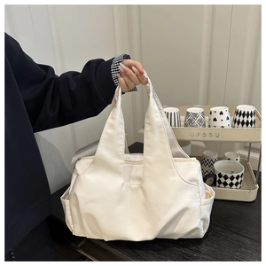 Detailed view of cream nylon tote bag featuring U-shaped handles and side pockets