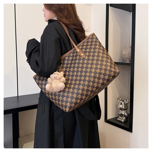 Detail of checkered tote bag with Z-pattern and plush bear charm worn by a model