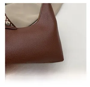 Detailansicht der braunen Lederhandtasche mit Litschi-Maserung und einem karierten Seidentuch