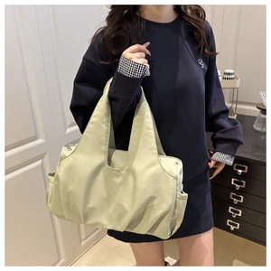 Detailed side view of light green pleated tote bag worn by a model in casual setting