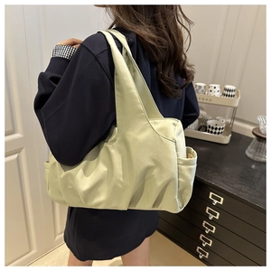 Detail view of the large light green pleated tote bag with side pocket and wide strap