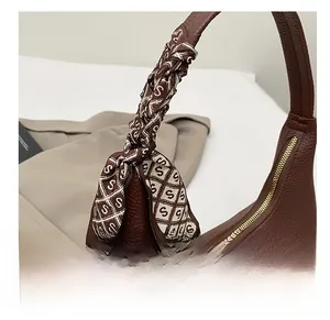 Detail einer dunkelbraunen Shopper aus Leder mit einem dekorativen Seidenschal am Griff