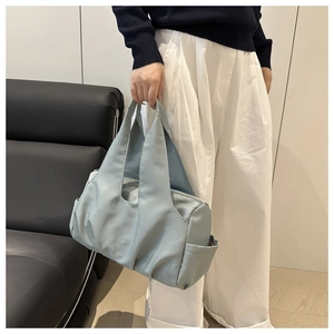 Detail of light blue pleated tote bag with wide strap and side pocket on sofa
