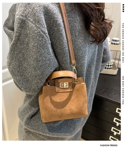 Detail view of brown faux suede crossbody bag with gold metallic twist lock and top handle