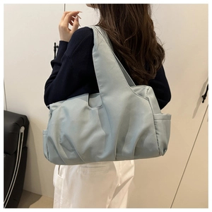 Close-up of lightweight blue nylon tote bag showing side pocket and spacious design