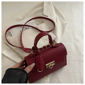 Close-up of litchi grain leather texture on wine red crossbody bag with gold buckle