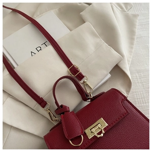 Close-up of burgundy lychee leather handbag with vintage gold swivel lock and strap detail