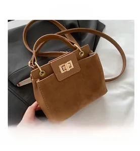 Close-up of contrast texture brown suede handbag with golden metal turn-lock closure