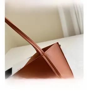 Close-up of brown leather tote bag showing detailed stitching and premium texture