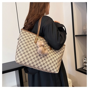 Detail view of jacquard canvas tote bag with brown leather handles and a cute bear charm