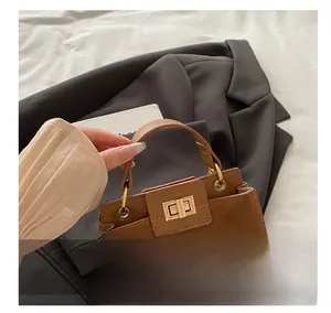 Detail of a brown suede and leather handbag featuring a gold square twist lock