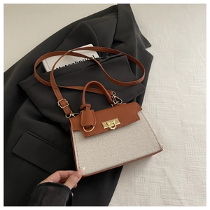 Detail of color-block trapezoid handbag with gold hardware on a black blazer background