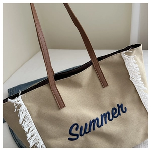 Gros plan d'un sac en toile beige avec broderie Summer et bords décoratifs à franges
