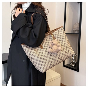 Detail of French tote bag with brown leather trim and cute plush bear accessory