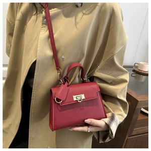 Detail of red lychee textured handbag featuring golden clasp and elegant top handle