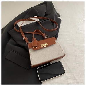 Detail of elegant contrast stitching bag with gold lock buckle and leather strap