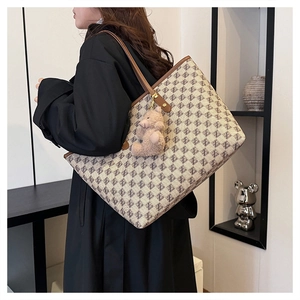 Detail of vintage monogram tote bag with brown leather trim and cute bear charm on a model