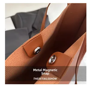 Detail view of magnetic metal snap closure on a vintage brown leather tote bag