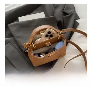 Detailed view showing inner storage for phone and cosmetics in brown suede shoulder bag