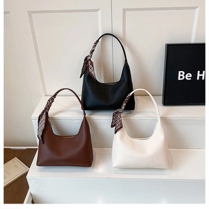 Nahaufnahme minimalistischer Lederhandtaschen in Schwarz, Braun und Weiß mit Halstüchern