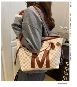 Close-up of large capacity tote bag featuring all-over M letter print and leather patch