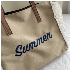 Détail du cabas en toile beige avec broderie Summer bleue et anse en cuir
