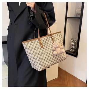 French style tote bag detail with monogram pattern, leather straps and a pink teddy bear charm