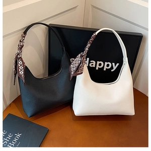 Close-up of black and white lychee leather handbags decorated with printed silk scarves