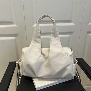 Minimalist off-white nylon tote bag with side pockets and top handles on a chair