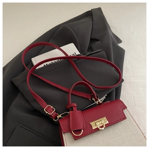 Close-up of contrast-color leather handbag with golden twist lock on a blazer