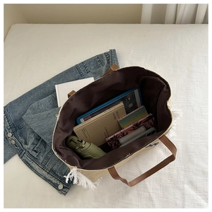 Détail du grand sac cabas en toile beige montrant l'espace intérieur et les franges