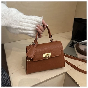 Detailed shot of brown lychee-grain leather handbag with elegant gold twist-lock closure