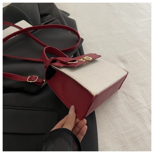 Detail of burgundy lychee leather and beige woven fabric on a mini crossbody bag