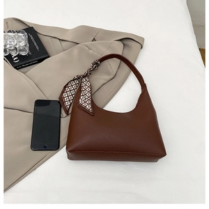 Detail of dark brown lychee leather handbag with decorative geometric silk scarf accent