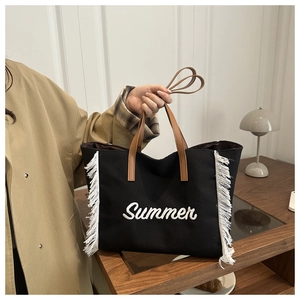Détail du sac cabas en toile noire avec broderie Summer blanche et finitions à franges