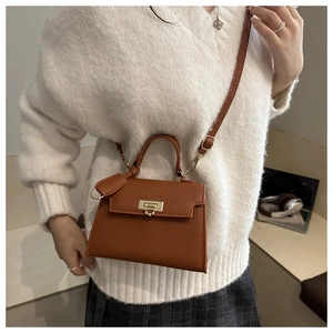 Detail of a brown leather handbag with a gold twist lock and a textured finish